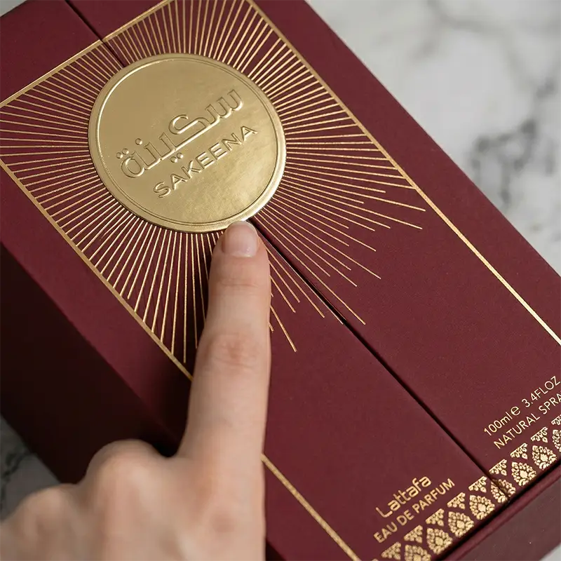 Embossed gold Sakeena logo and textured detailing on the maroon velvet perfume packaging.